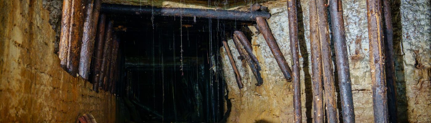 An Abandoned Mine Tunnel with Wooden Supports, Water Dripping, and Dark Shadows Everywhere