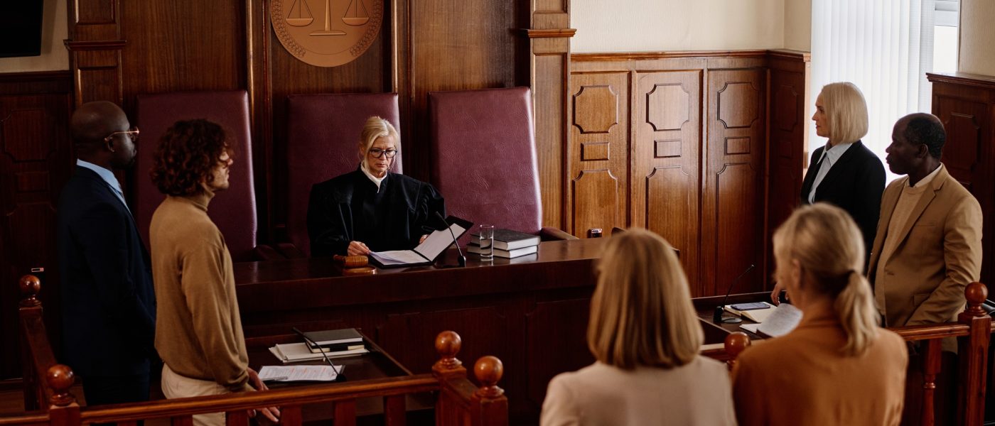 Group of witnesses, attorneys, prosecutor and suspect standing in courtroom