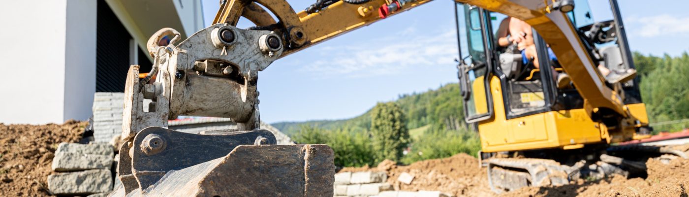 Mini excavator digging preparing ground under home garden