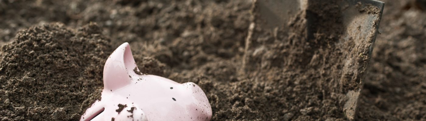 Shovel digging up piggy bank